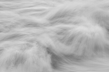 Monotone long-exposure view of moving water forming soft swirling patterns and blurred textures
