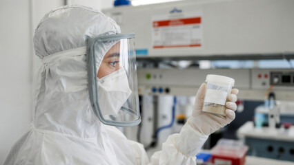 Scientist in Full PPE Examining a Biological Sample in a Laboratory with Fume Hood