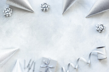 Silver party decoration - streamers with confetti and cones on gray stone background, top view