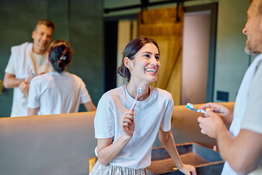 Young couple smiling and laughing in bathroom, brushing teeth together. Sharing a morning routine, expressing happiness and connection