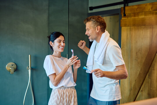 Happy couple engaging in their morning teeth brushing routine, sharing a playful and affectionate moment in the bathroom