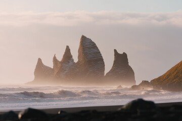Dramatic coastal rock formations rising from ocean waves under a hazy sky