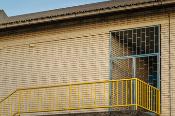 yellow metal railing and grid blue door on brick wall exterior