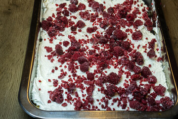 homemade tray of whipped cream dessert topped with frozen raspberries