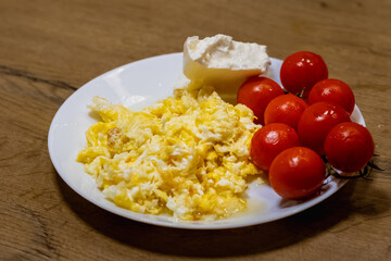 scrambled eggs with fresh cherry tomatoes on white plate