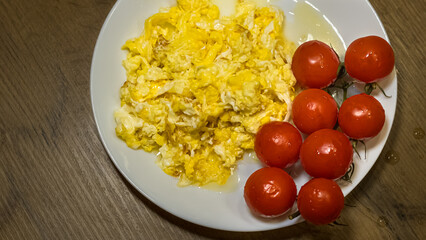 scrambled eggs with fresh cherry tomatoes on white plate
