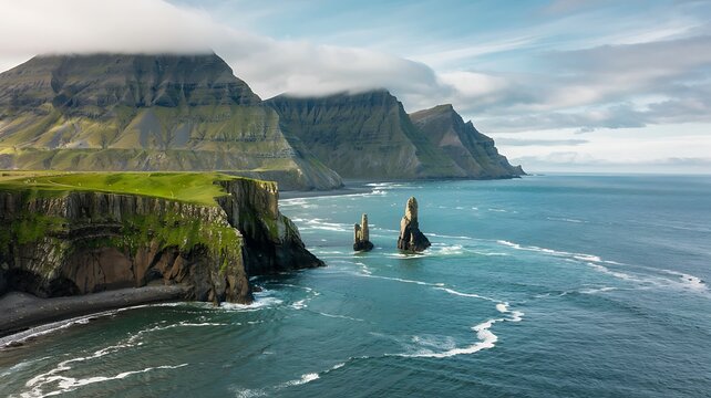Dramatic icelandic coastline with towering sea stacks and rugged cliffs meeting the turbulent ocean waves under a cloudy sky