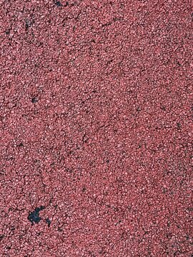 Full frame background of red granular rubber texture or synthetic athletic track surface