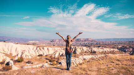Traveler woman enjoying amazing view of panoramic wilderness landscape, cliff, mountain and valley. Travel, exploration,adventure concept in Cappadocia