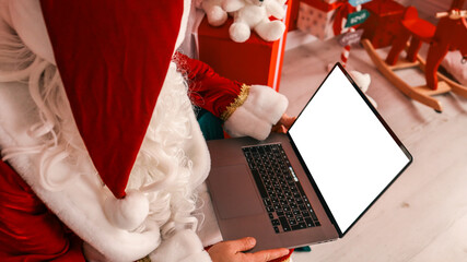 Santa Claus using a laptop to check his list and prepare for Christmas