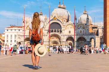 backview of traveler woman visiting city of Venice in Italy. San Marco square