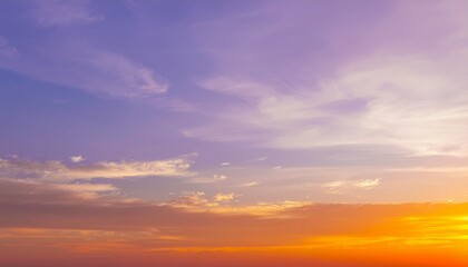 Fototapeta premium A serene sunrise spreads warm orange and purple hues across the sky, gently illuminating the horizon above a calm, shadowed landscape