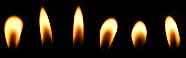 A candle flame is burning at night in close range, yellow light isolated on a black background....