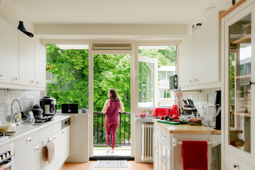 Midlife coach looks outdoors in quiet morning home setting