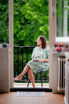 Midlife woman pauses journaling to look at trees outside