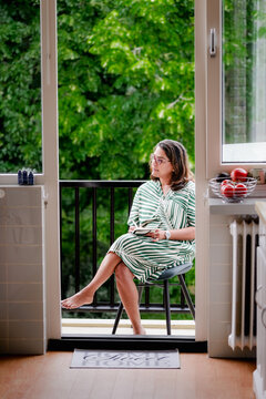 Journaling woman sits peacefully on balcony chair