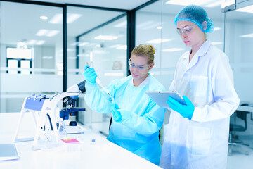 scientists collaborate on assay development, with one performing a critical pipetting step while...