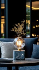 A decorative desk lamp with a marble base, a large glass Edison bulb, and a dried plant stem, set on a table.