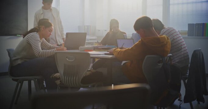 Students Collaborate on Laptops in Bright Classroom. Boy Sits Down at Table and Joins Teamwork. Concept Group Project Work, and Essential Role of Digital Learning in Modern Educational Setting.