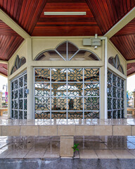 Raja Ayang Mausoleum, Bandar Seri Begawan, Brunei. Ornate patterned windows, rich wooden ceiling, and reflective tiled floor of the historic structure.