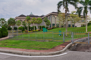 Prime Minister's Office, Bandar Seri Begawan, Brunei. Exterior view of the grand building with lush gardens, palm trees, and a decorative fence.