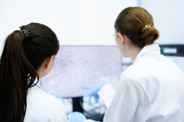 Fototapeta premium A pharmaceutical Quality Control QC team ensures GxP compliance. Two scientists review an electronic batch record on a tablet while a third performs a required analytical test.