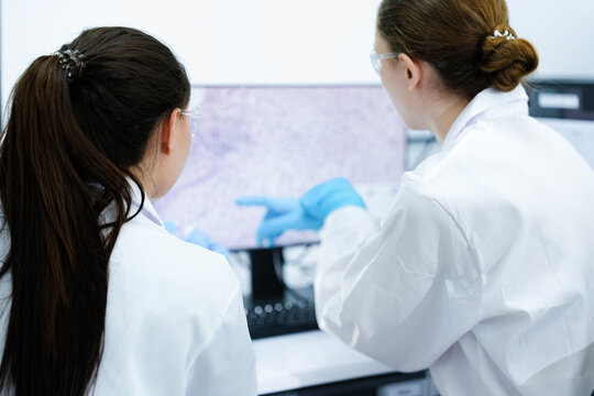 A pharmaceutical Quality Control QC team ensures GxP compliance. Two scientists review an electronic batch record on a tablet while a third performs a required analytical test.