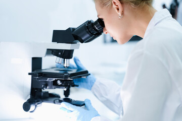 A pharmaceutical Quality Control QC team ensures GxP compliance. Two scientists review an electronic batch record on a tablet while a third performs a required analytical test.