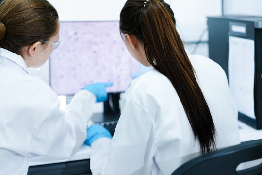 A pharmaceutical Quality Control QC team ensures GxP compliance. Two scientists review an electronic batch record on a tablet while a third performs a required analytical test.