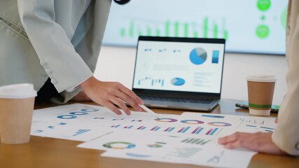Business team collaborating on financial data and analytics in a modern office. Two colleagues are reviewing charts and graphs while discussing results with a laptop data visuals in the background - Powered by Adobe