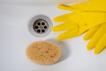 Close-up of sink drain and yellow gloves