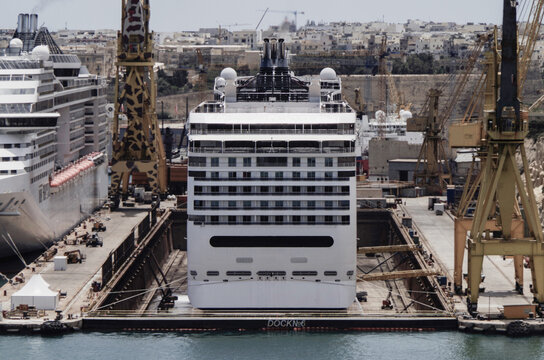 Modern cruise ship cruiseship liner Divina and Magnifica being modernized over-hauled repaired refitted maintenanced by shipyard in Malta with dock and cranes	