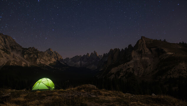 Camping under the stars: a glowing tent in the mountains at night