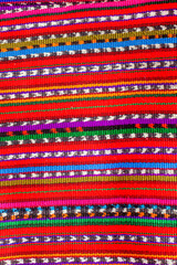 Colorful striped Guatemalan fabric with a red background
