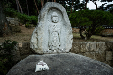 Offering pouch placed before a carved stone Buddha statue at a temple site in Seoul, South Korea