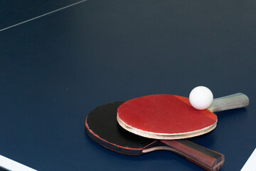Ping Pong Ready Paddles and ball await the next game on blue table.