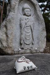 Offering pouch placed before a carved stone Buddha statue at a temple site in Seoul, South Korea