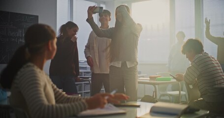 Group of Happy Students Gathers Front of Bright Classroom Take Group Selfie With Smartphone, Smiling and Making Peace Signs. Concept of Social Interaction and Youth Culture During Break in Study Day.