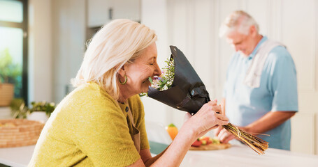 Smell, flowers and woman or couple cooking in kitchen of home for anniversary celebration, romance or gift. Love, present or bouquet with senior man in house for floral scent and meal prep with smile