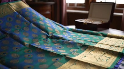 Opulent indian wedding preparation detail showing rich turquoise silk saree and gold bridal jewelry accessories