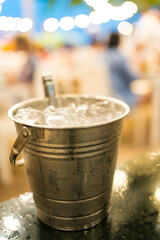Metal ice bucket filled with ice cubes with tongs