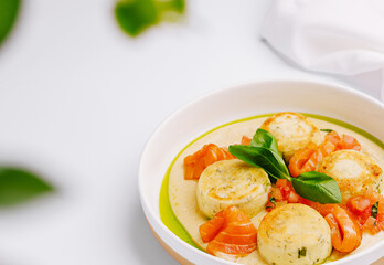Creamy herb dish with tomatoes served in a white bowl on a light background
