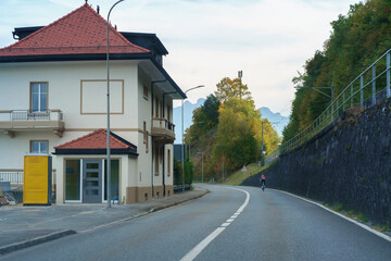 man rides bicycle on quiet and empty mountain road in small alpine town
