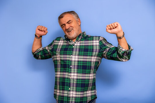 Senior man yawning and stretching feeling tired on blue background - Powered by Adobe