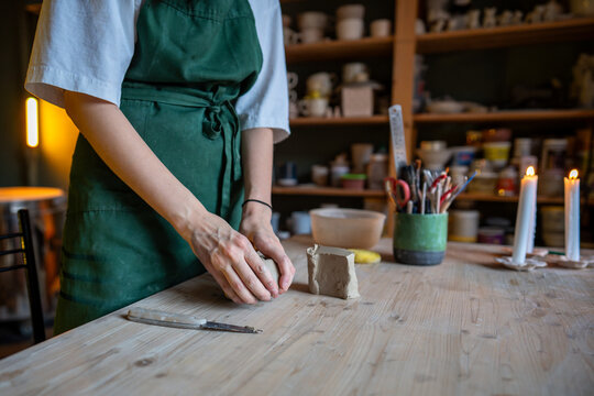 Female potter artist molding raw clay. Closeup of woman ceramist in apron prepare for shaping pottery. Craftswoman hands work with earthenware. Cozy art studio production and craftsmanship therapy - Powered by Adobe