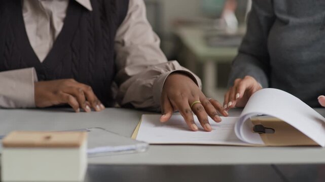 Cropped shot of hands of unrecognizable diverse female colleagues working on business report together in office