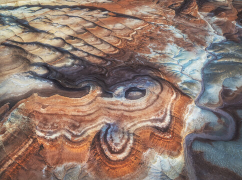 Aerial view of the intricate, layered landscape carved by time and elements, revealing a symphony of earthy hues and textures, Hanksville, Utah, United States.