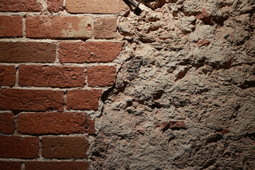 A Grunge Background Split Between Exposed Red Bricks And Uneven Grey Cement Plaster. A Contrast Of Materials And Textures.