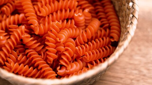 Orange lentil fusilli pasta in a rustic bowl. Uncooked organic diet ingredient close up