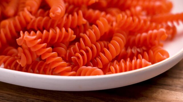 Italian orange lentil fusilli pasta on a ceramic plate close up